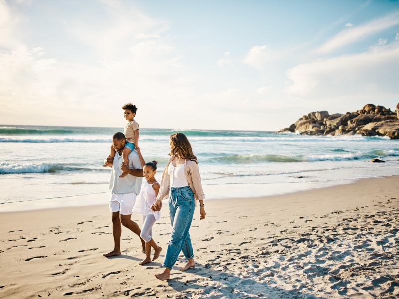 A family walking on the beach with gentle waves coming in on the sand.