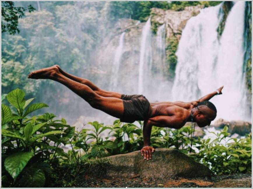 Performer balancing on a rock in front of a waterfall.
