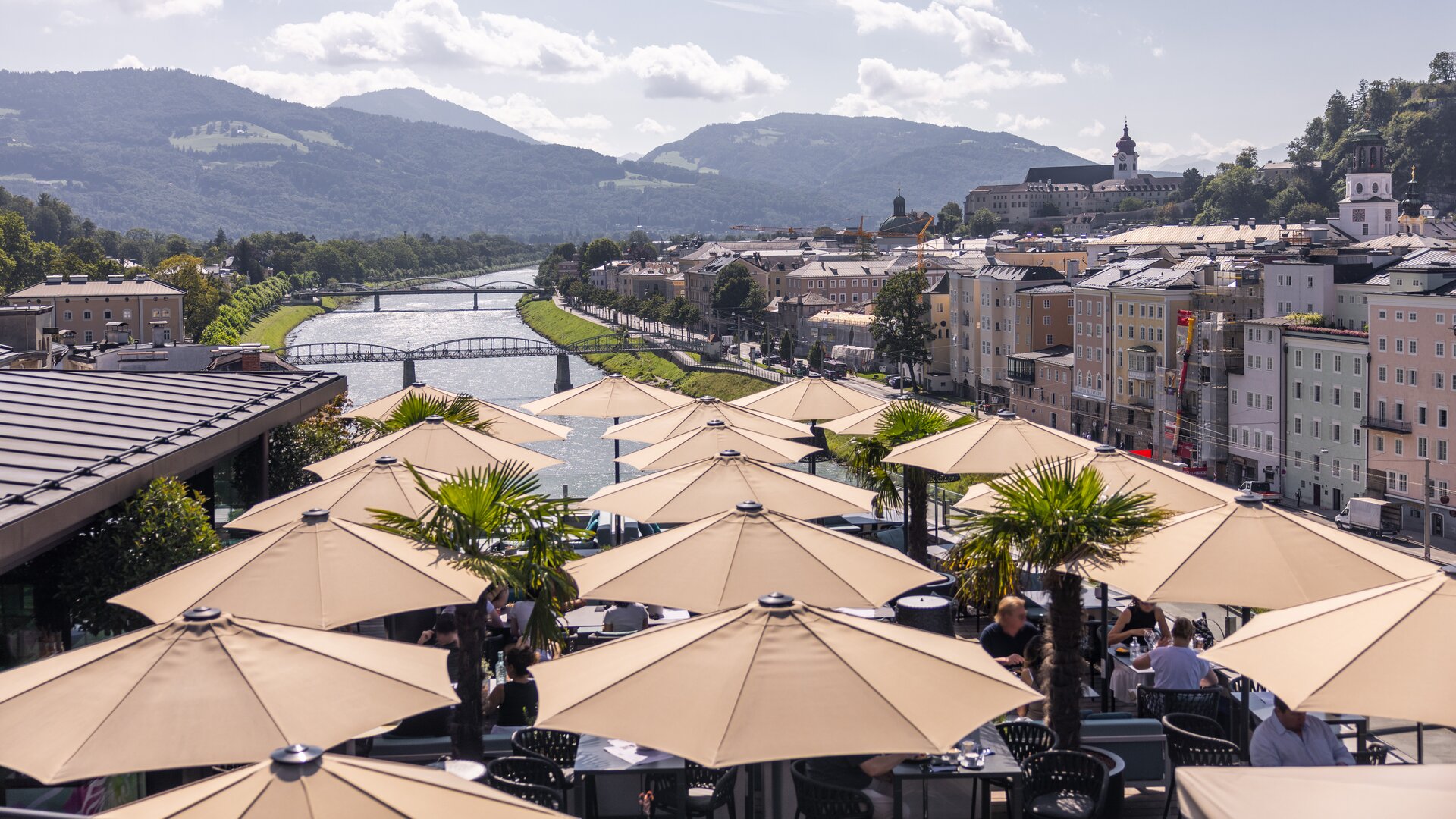 Steinterrasse Rooftop Restaurant Dining Tables with Parasols and View of River with Mountains in the Background