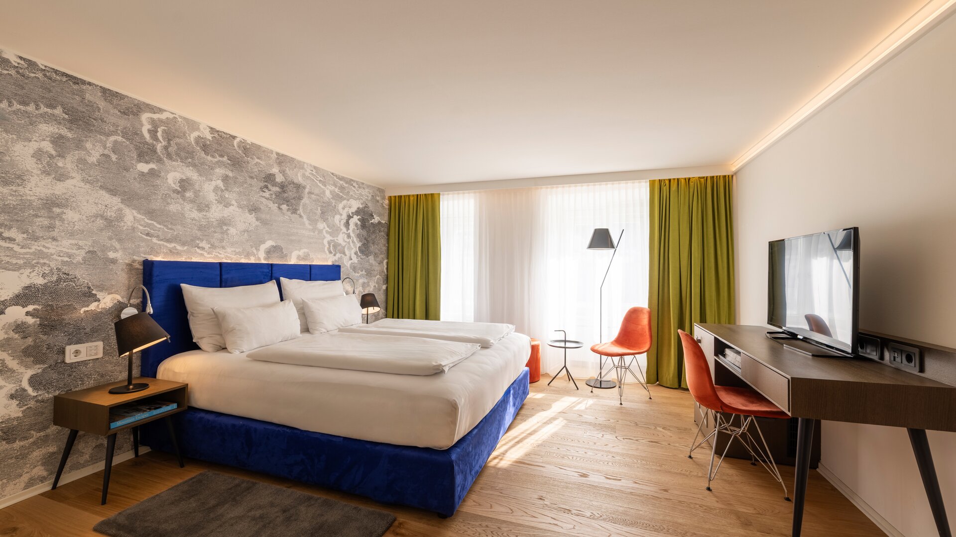 Standard Guestroom with Blue, Green and Orange Décor Accents, and an Accent Wall of Black & White Patterned Wallpaper