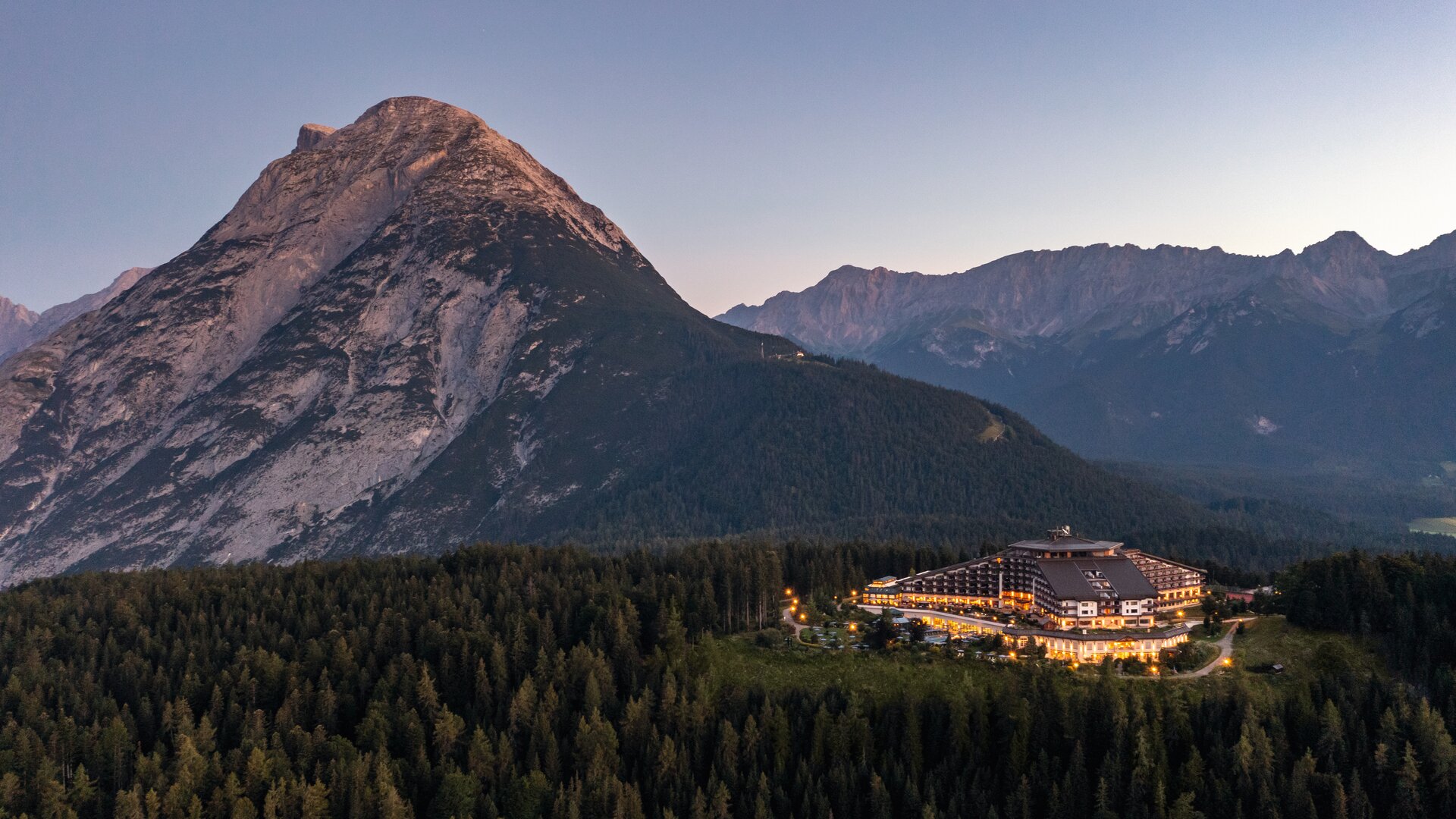 Interalpen-Hotel Tyrol | Exterior Wide Shot Evening View with Surrounding Mountains and Landscape