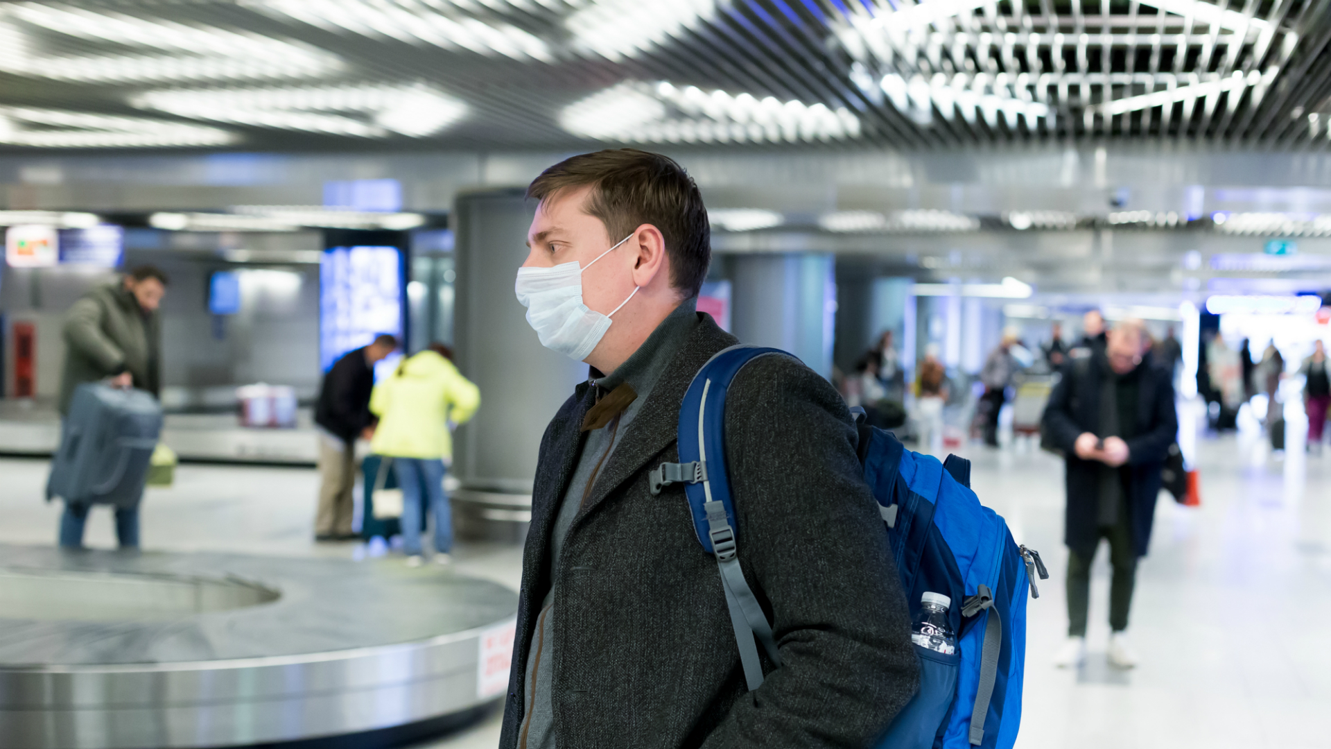 man wearing face mask in airport baggage claim