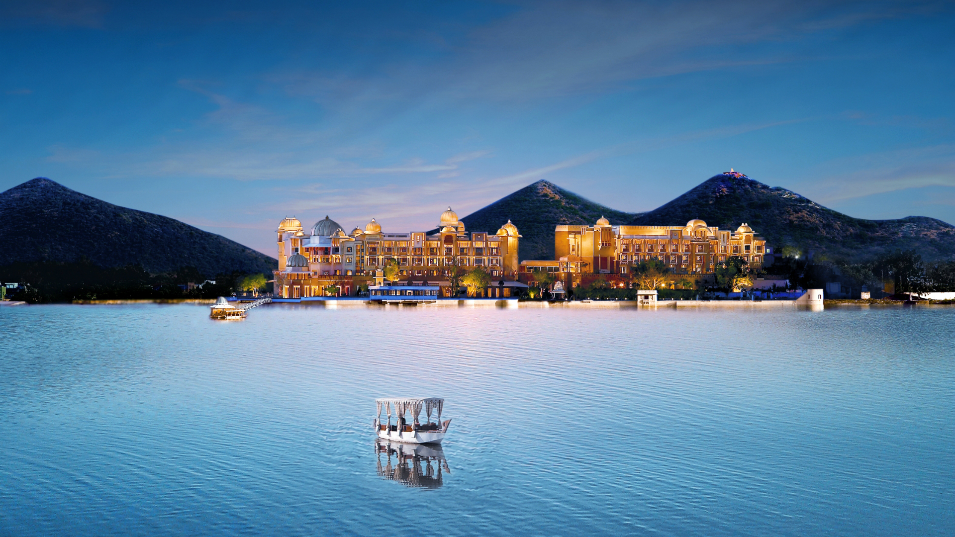 leela palaces udaipur on lake at dusk with boat in foreground