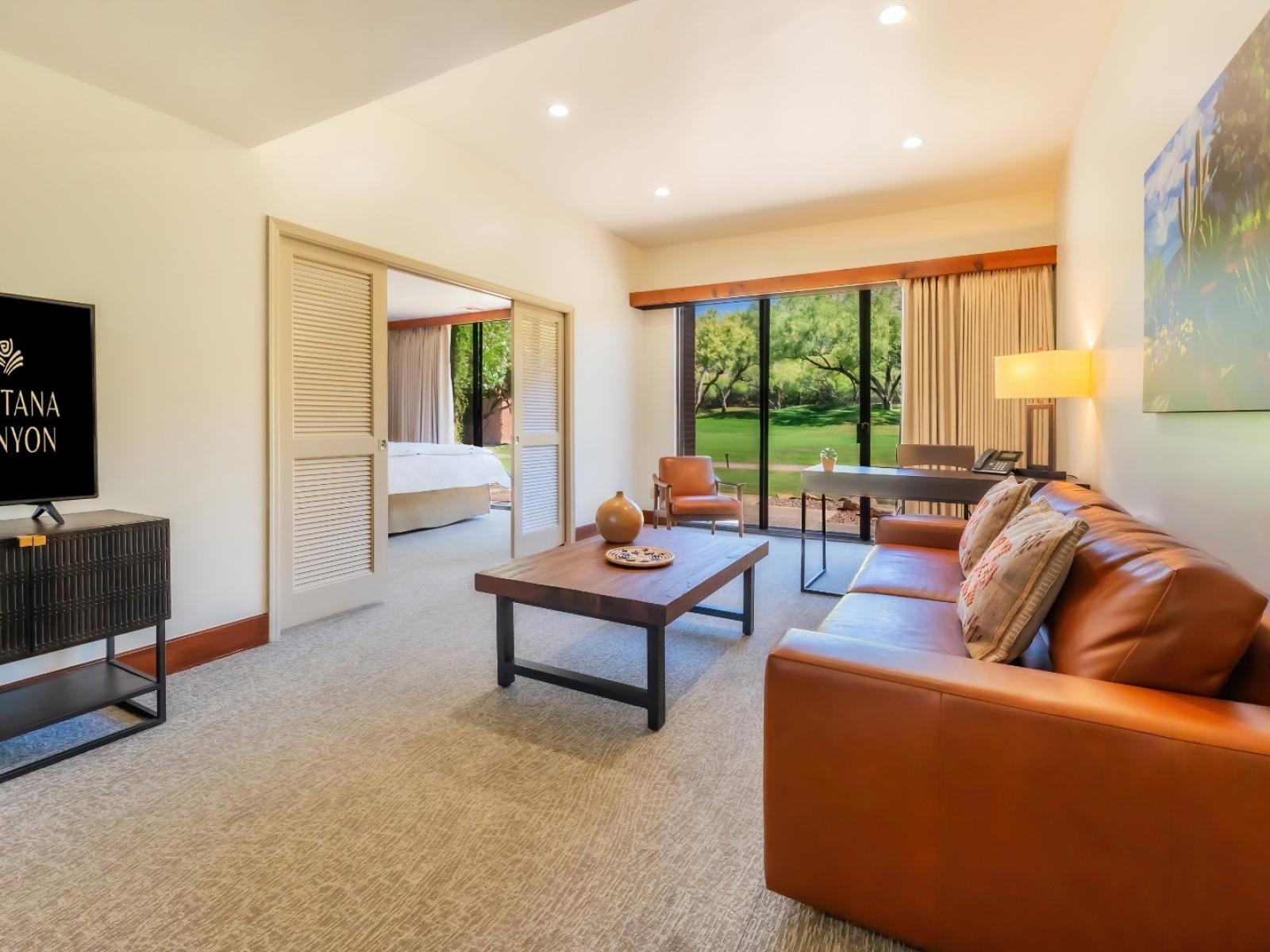 The living room from the Mountain View Suite, with a couch, desk, and television, and sliding doors to the bedroom.