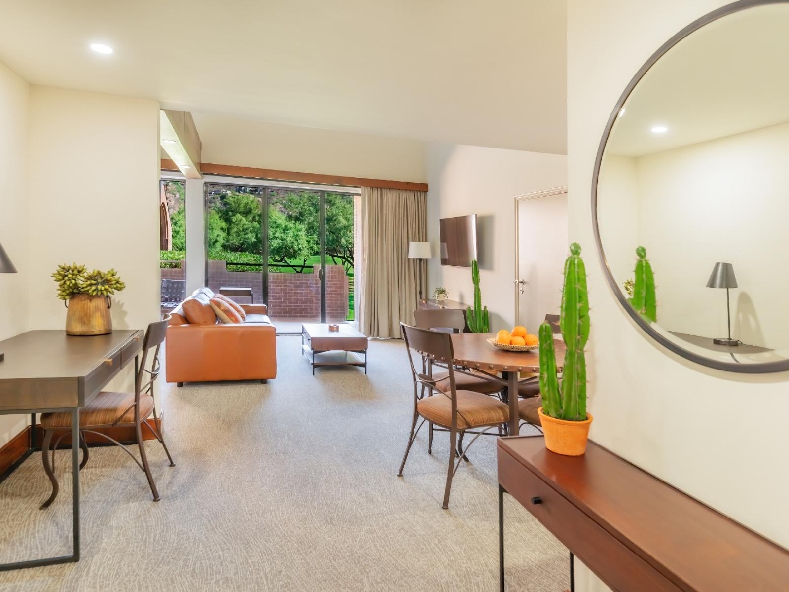 A living room area with the couch and dining table, and the patio door at the back of the image. 