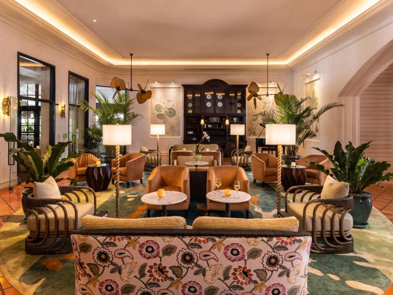 The Palms Hotel & Spa comfy lobby lounge with caramel‑tan armchairs, lush green accents, and soft warm lighting framed by bold patterned upholstery.