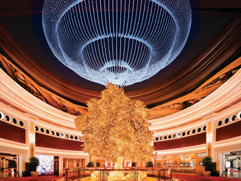 Beneath a dazzling crystal chandelier, the resort’s attraction centerpiece golden tree radiates opulence with shimmering gold tones, ivory architectural details, and rich crimson accents.