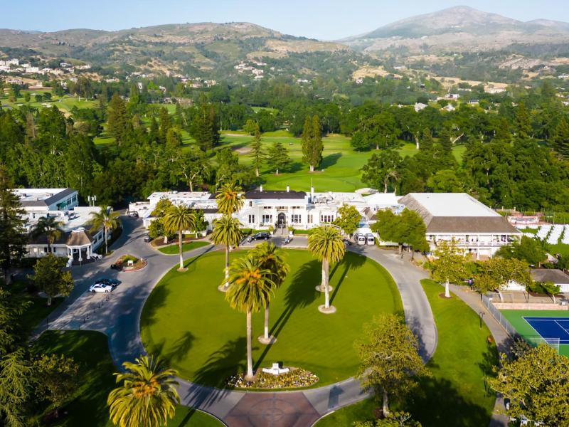 Breathtaking aerial view of Silverado Resort with lush green golf courses accented by vibrant palm trees and deep blue tennis courts.