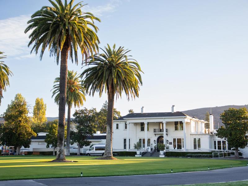 Silverado Resort timeless and charming exterior framed by towering palm trees and rich green lawns against a serene mountain backdrop.