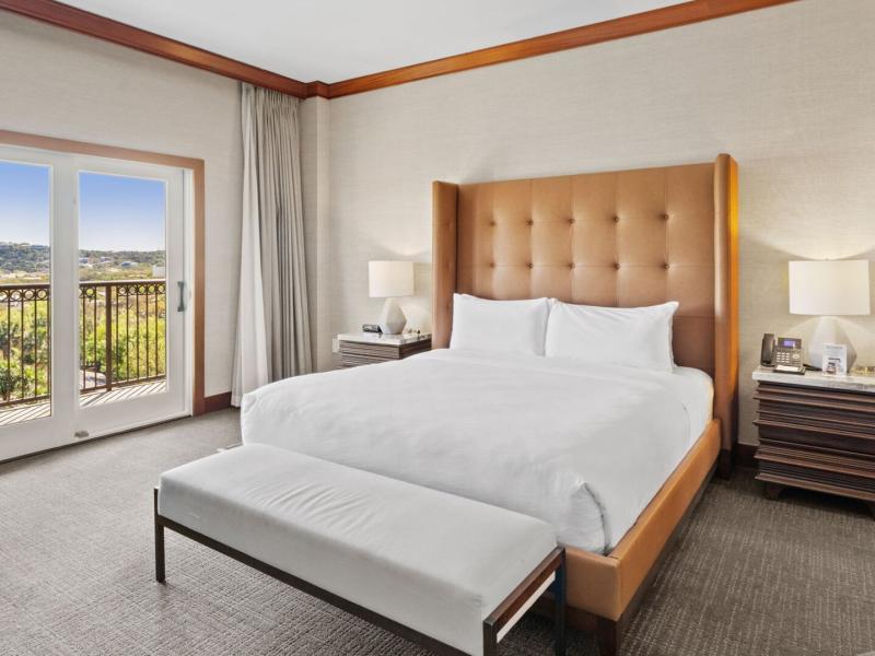 Palm Presidential Suite sophisticated bedroom features a plush king bed, elegant wood accents, and a private balcony offering stunning views of the surrounding landscape.