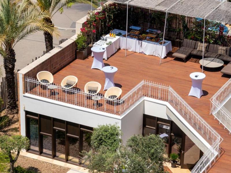 The Tagomago event space offers a stylish rooftop terrace surrounded by lush palms and chic lounge seating for an unforgettable event.