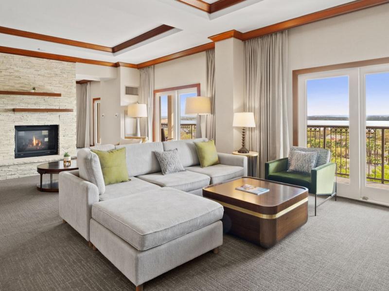 Palm Presidential Suite spacious, elegantly furnished living area features a cozy fireplace, plush seating, and large windows opening to stunning panoramic views.