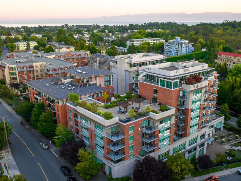 The Parkside Hotel & Spa modern exterior showcasing a multi-story building surrounded by lush greenery, offering spacious balconies and rooftop gardens in a vibrant urban setting.