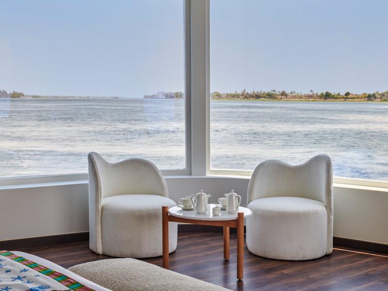 Cabin suite cozy seating area with sweeping views of the tranquil river from expansive picture windows.