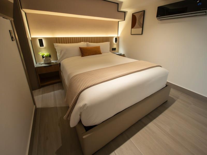 Cozy Dovle Branded Residences guest bedroom with a plush bed, warm lighting, and modern minimalist design for ultimate comfort.