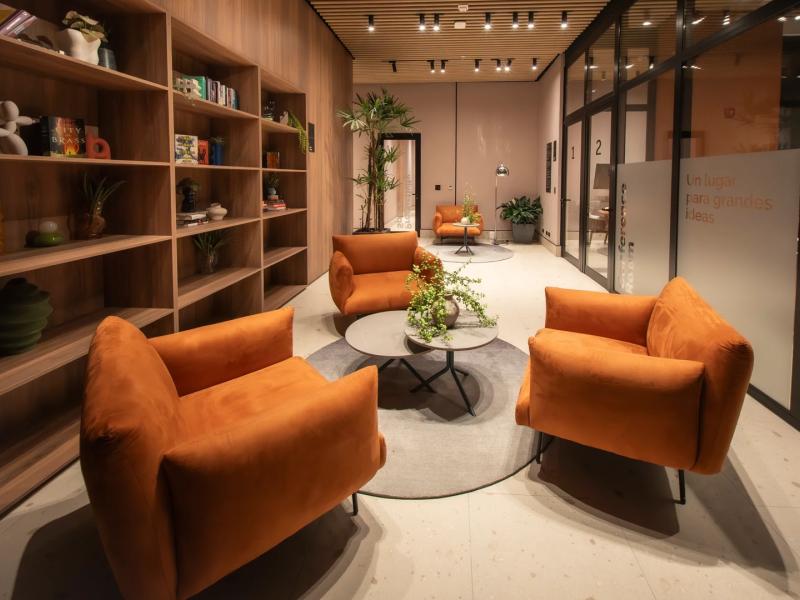 Dovle Branded Residences cozy lounge & library with vibrant orange armchairs, sleek shelving, and warm lighting for a stylish, inviting atmosphere.