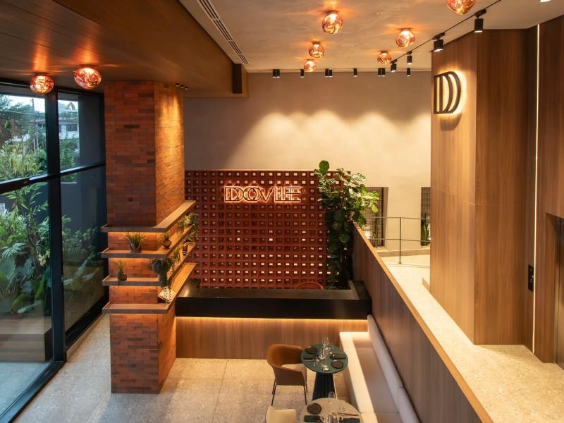 Dovile Branded Residences elegant lobby featuring warm wood accents, natural light, and greenery for a welcoming modern ambiance.