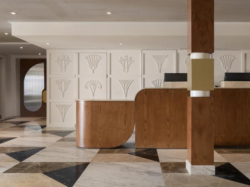 Showcasing a sleek, modern lobby reception with elegant geometric flooring, warm wood accents, and art-deco inspired wall panels for a sophisticated first impression.