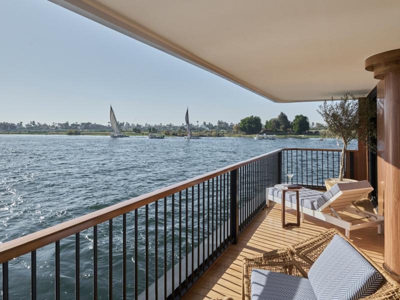 Spacious, shaded private suite balcony—elegantly furnished—invites sun‑soaked moments over sweeping water vistas.