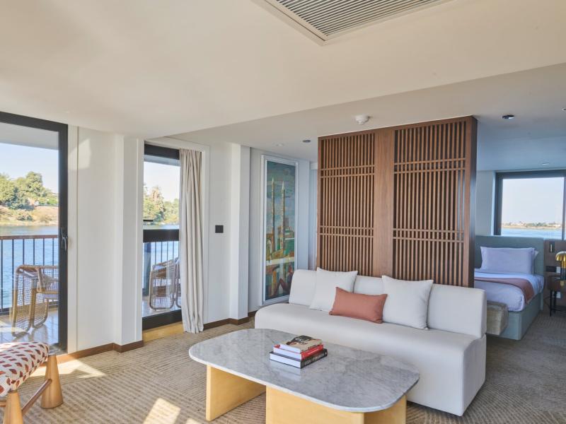 Stylish suite with a cozy lounge area, marble coffee table, modern wood accents, and expansive windows framing the tranquil water scenery.