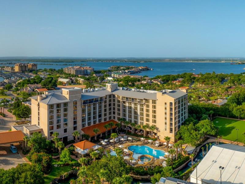 View of Horseshoe Bay Resort with its sparkling pool and lush greenery overlooks a scenic bay and vibrant coastal landscape.
