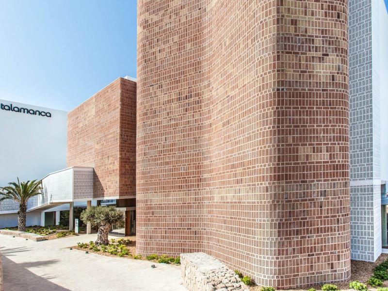 Showcasing a sleek modern design with striking brick textures, clean white facades, and lush Mediterranean landscaping, Ocean Drive Talamanca offers a stylish and inviting architectural exterior.
