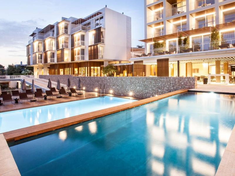 The contemporary hotel design blends luxury and comfort with a stunning infinity-style pool, and black modern loungers.