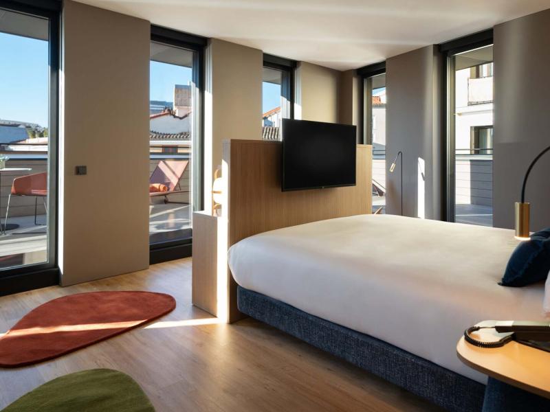 Stylish Corner Deluxe Terrace Guestroom featuring a plush king bed, modern décor, and floor-to-ceiling windows opening to a private terrace.