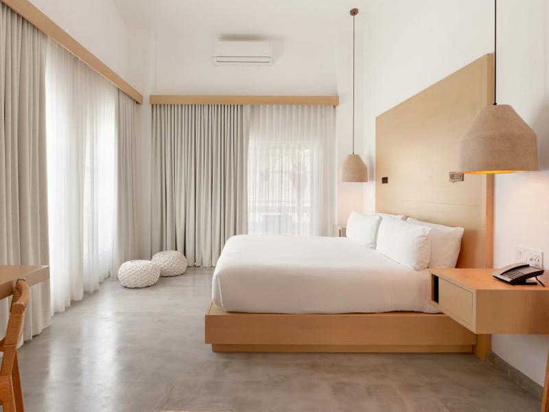 A serene loft bedroom with a sleek platform bed and pendant lights, accented by soft beige tones and light gray curtains for a modern, airy feel.