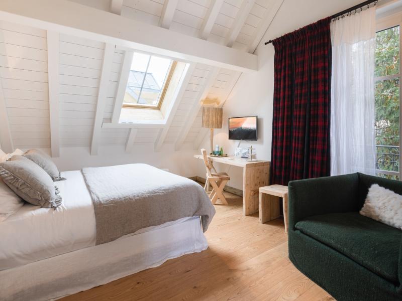 Showcasing bright white beams and a skylight, this Chalet bedroom is accented with deep green seating and rich burgundy curtains.
