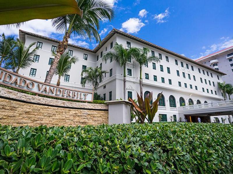 Condado Vanderbilt Hotel's majestic façade surrounded by lush greenery and palm trees welcomes guests to an oasis of sophistication and comfort.