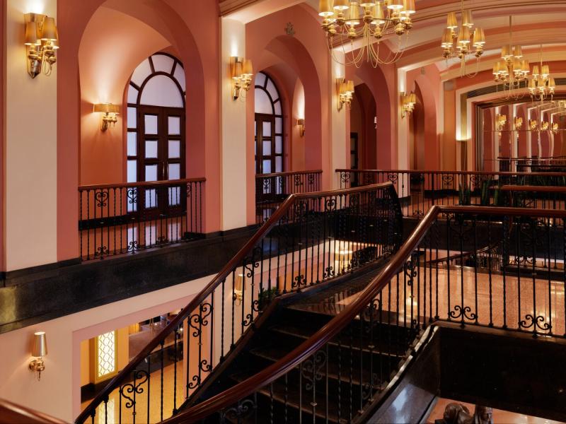 Condado Vanderbilt Hotel stunning grand staircase framed by elegant arches and sparkling chandeliers creating a timeless, luxurious ambiance.