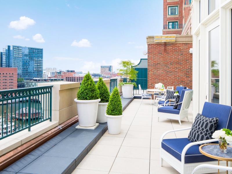 John Adams Presidential Suite spacious terrace with plush navy seating and crisp white planters, complemented by lush greenery and stunning cityscape views.