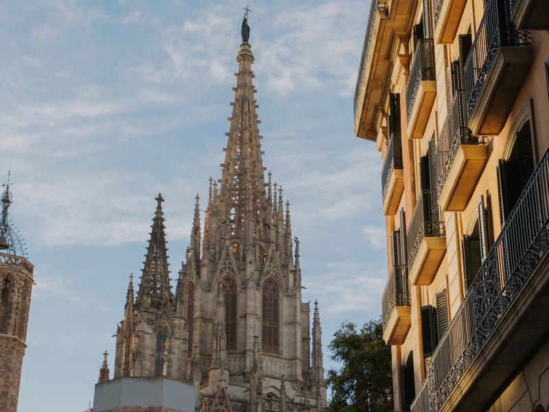 Set in the Gothic Quarter, Lamaro Hotel features views of the Barcelona Cathedral with it’s intricate Gothic spires set against a soft blue sky, paired with the hotel’s ornate wrought-iron balconies and golden-hued building details for a timeless cityscape.