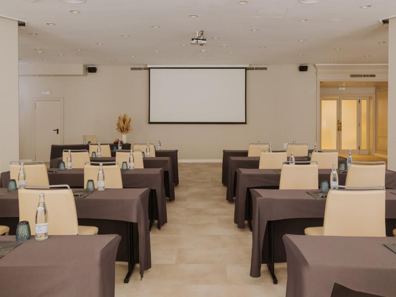 Marina Room event space featuring a conference setting with sleek dark brown table covers and beige chairs, complemented by soft neutral walls and subtle blue glass accents.
