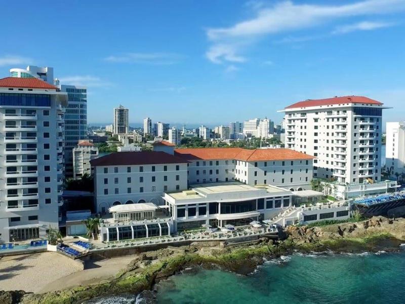 Condado Vanderbilt Hotel stunning oceanfront property with crisp white façades and vibrant terracotta rooftops, framed by turquoise waters and a clear blue sky.