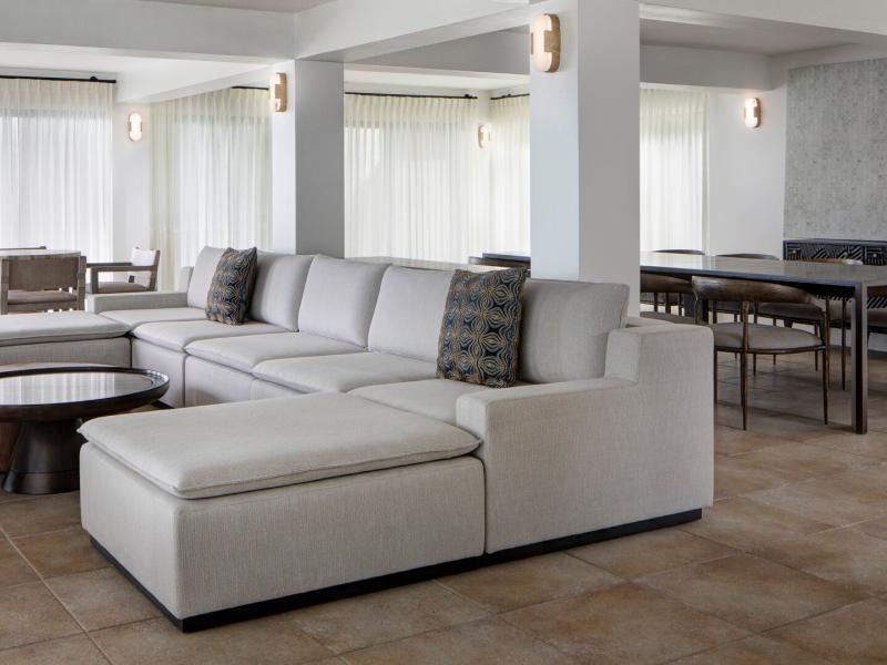 The spacious living area of Hawk's Nest villa featuring a plush ivory sectional and modern dining space, accented by warm taupe tiles and charcoal details.