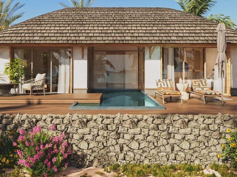 ENVI Paje luxurious Signature beachfront Villa exterior with a private pool and spacious wooden deck, accented by natural stone walls and vibrant green palm trees.