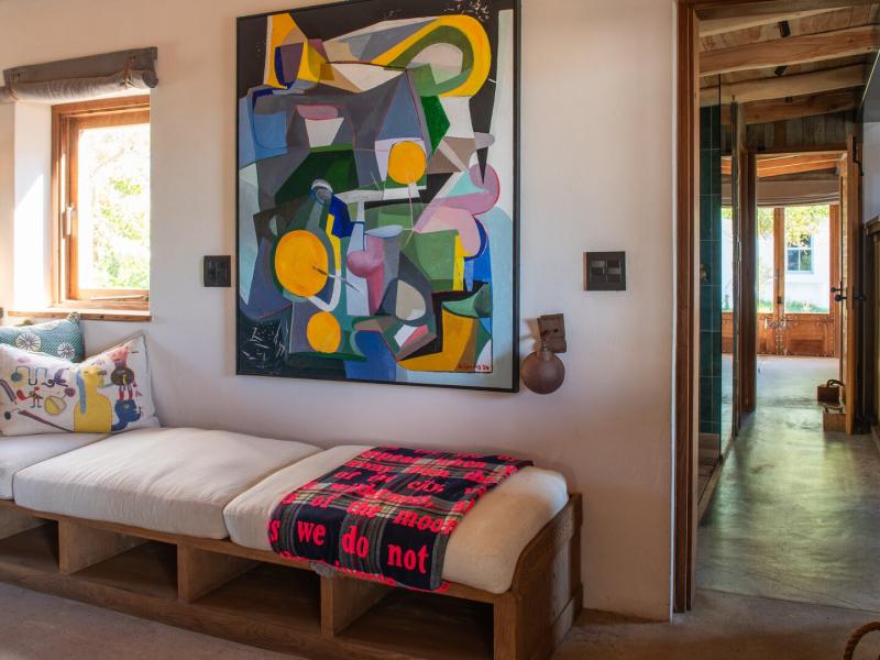 Yellowwood Cottage Lounge space with bold pops of color from the vibrant abstract artwork and a cozy built-in bench with plush cushions striking red plaid throw, set against warm wood accents and neutral beige walls for a modern yet cozy vibe.