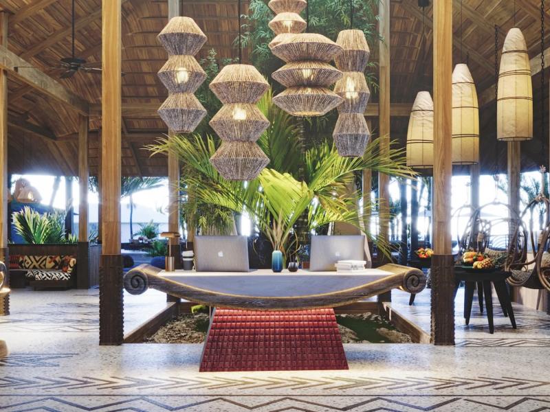 ENVI Paje striking reception space featuring a sculptural wooden desk and bold woven pendant lights, complemented by green foliage and vibrant red and black accents