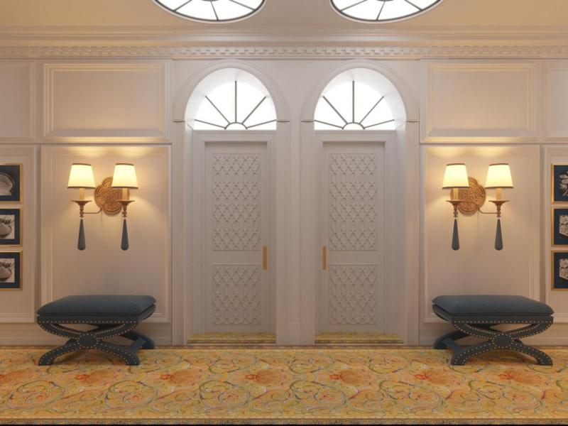 Gran Hotel Claridge Granada bright, classic guestrooms corridor with crisp white walls, navy seating accents, and golden sconces complemented by a warm, patterned carpet.