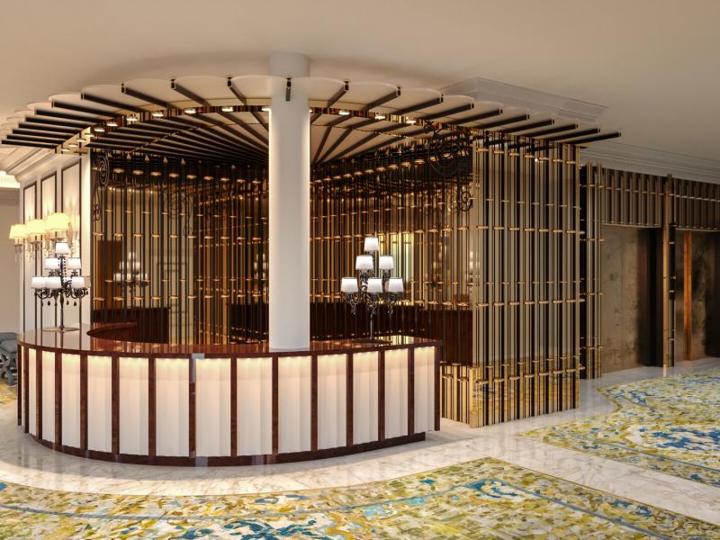 Gran Hotel Claridge Granada stylish lobby reception featuring a curved wood-and-marble desk, gold lattice accents, and a vibrant patterned carpet in green and blue hues.