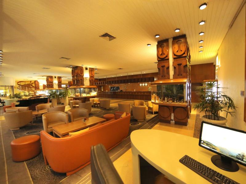 Hotel Carlton spacious, amber‑toned lounge features comfortable leather seating, sophisticated wood paneling, and subtle cream highlights for an inviting atmosphere.