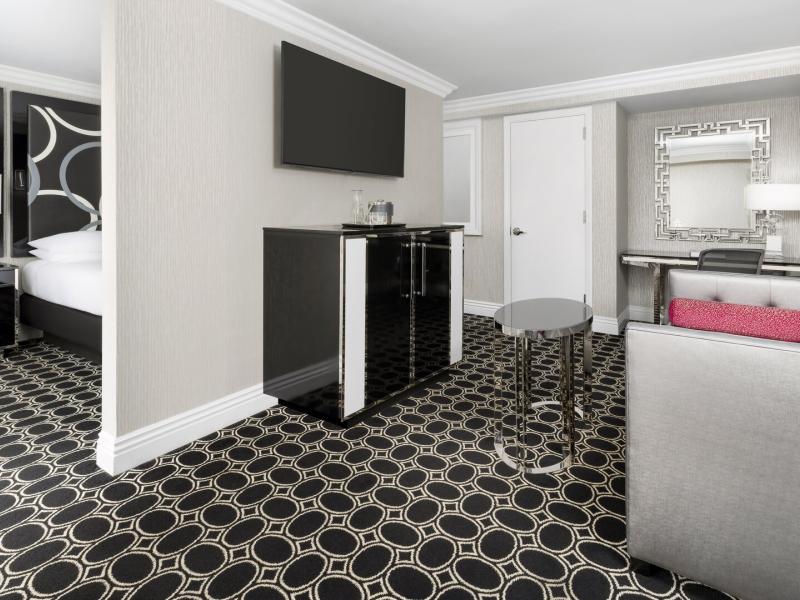 The Muse New York Muse Suite showcasing a bold black‑and‑white geometric carpet and glossy ebony furnishings accented by pops of silver and fuchsia.