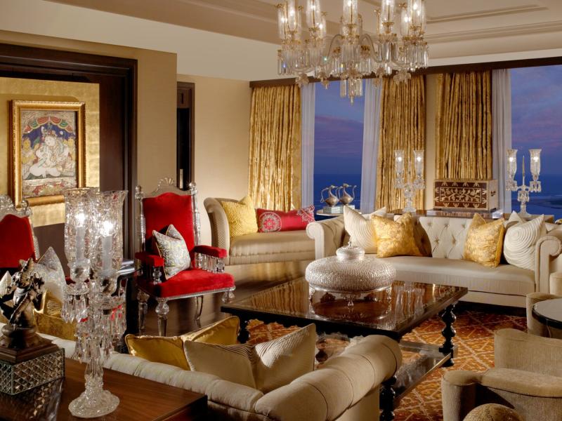 Royal Suite luxurious living space featuring crystal chandeliers, plush cream seating, and bold red and gold accents for a regal touch.
