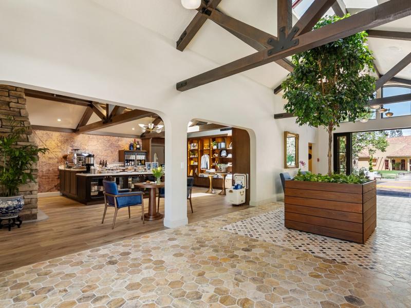 Vinarosa Resort & Spa airy lobby highlights exposed dark‑wood trusses and a lush central planter complemented by earthy tan and rich brown hues.