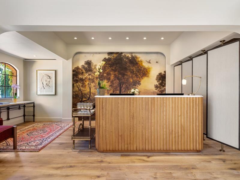 Vinarosa Resort & Spa’s refined reception area combines a wood‑slatted desk and mural backdrop with inviting burgundy and golden‑oak accents.