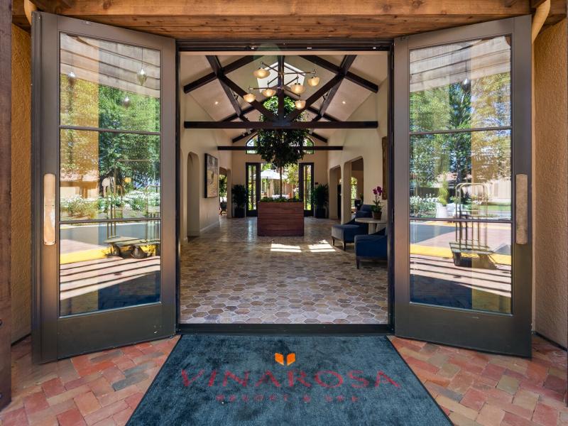 The grand entryway of Vinarosa Resort & Spa features expansive glass doors and rustic wood beams enhanced by deep charcoal and natural beige accents.