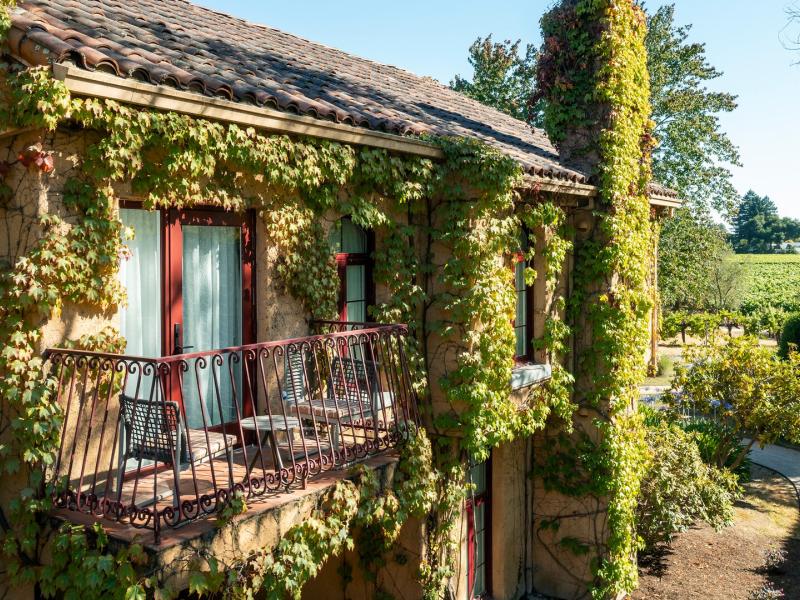 The picturesque grounds of Vinarosa Resort & Spa, a balcony wrapped in vibrant green vines overlooks serene pathways framed by rustic red and olive‑tone details.