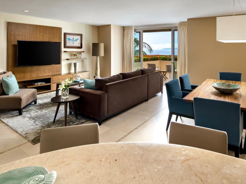 The spacious Family Suite at Grand Velas Riviera Nayarit with a comfortable living area, dining space, and balcony views, styled in warm neutrals with soft blue and natural wood accents.